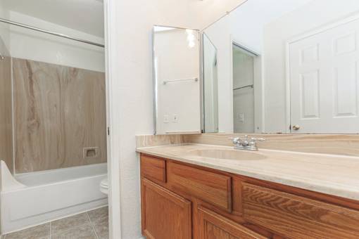 A bathroom with a wooden vanity and a white bathtub.