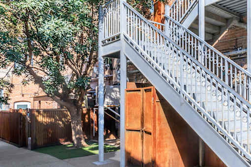 A white metal staircase with a tree in the background.