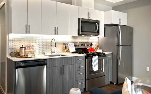 A modern kitchen with stainless steel appliances and a tiled backsplash.