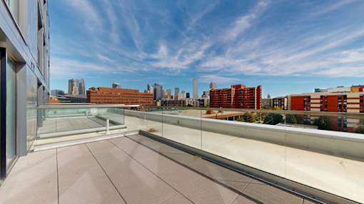 A balcony with a glass railing overlooking a cityscape.