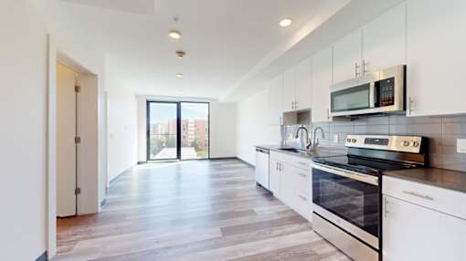 A modern kitchen with white cabinets and a black stove top oven.
