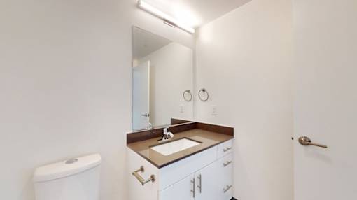 A bathroom with a toilet, sink, and mirror.