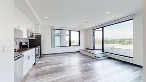 A modern kitchen with white cabinets and a large window overlooking the landscape.