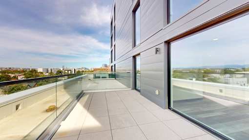 A balcony with glass railings and a view of the city.