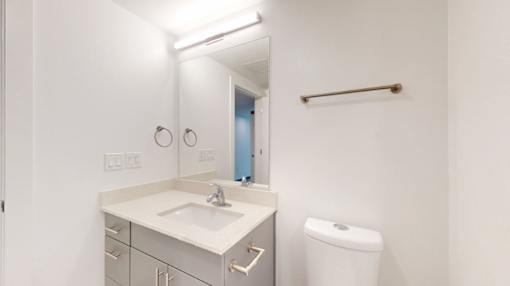A white bathroom with a sink, toilet, and mirror.