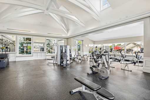 A spacious gym with a variety of equipment and a skylight.