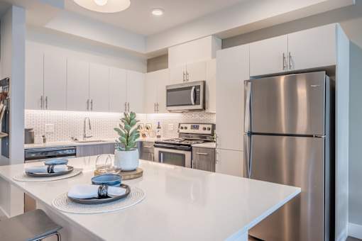 A modern kitchen with a white countertop and stainless steel appliances.