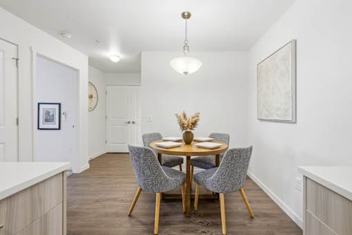 A dining room with a round table and grey chairs.