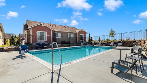 A pool with a diving board and a building in the background.