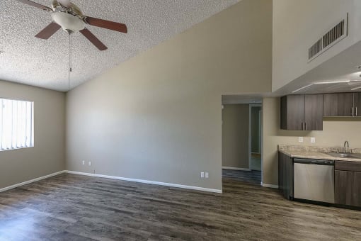 an empty living room and kitchen with a ceiling fan