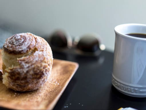 a doughnut on a cutting board next to a cup of coffee