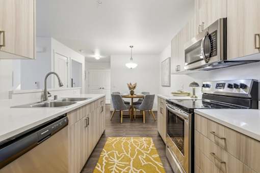 A modern kitchen with wooden cabinets and a yellow rug on the floor.