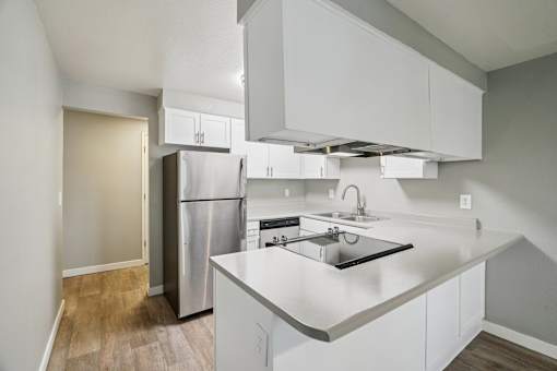 A kitchen with white cabinets and a stainless steel refrigerator.