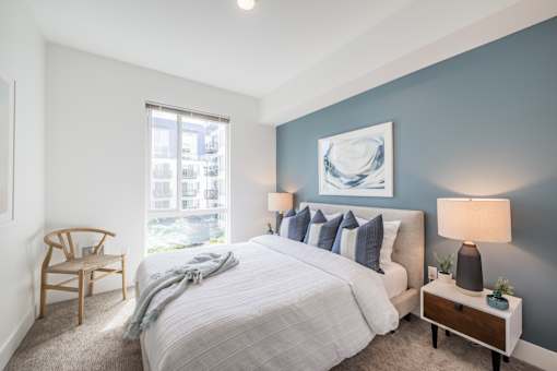 A bedroom with a large bed, a chair, and a window.
