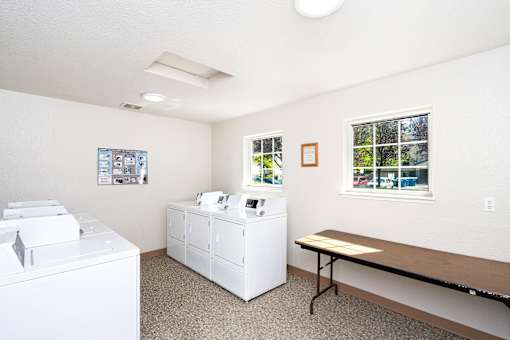 A laundry room with a washer and dryer, a table, and a window.