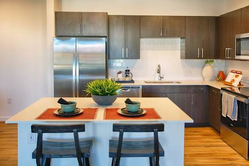 A kitchen with a white island and two chairs.