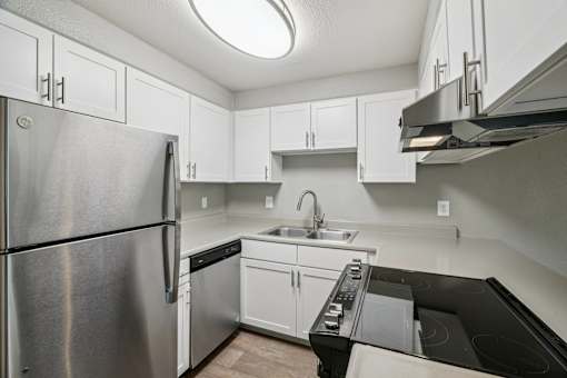A kitchen with a stainless steel refrigerator and black countertops.