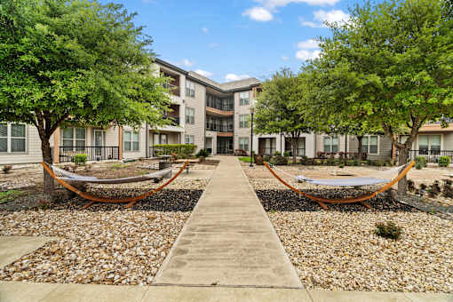 A walkway leads to a building with hammocks on either side.