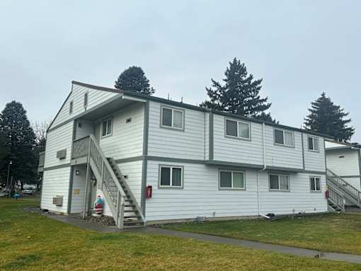 A white building with a grey roof and a staircase leading to the entrance.