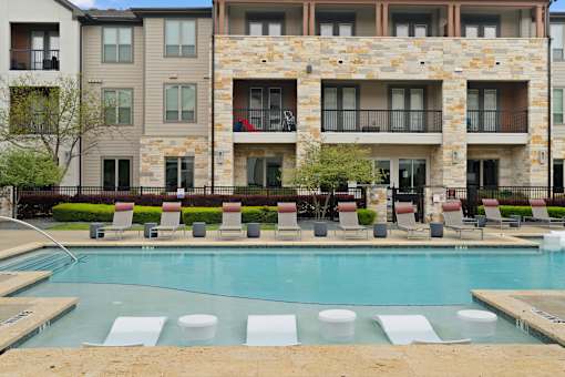 A large stone building with a pool in front.