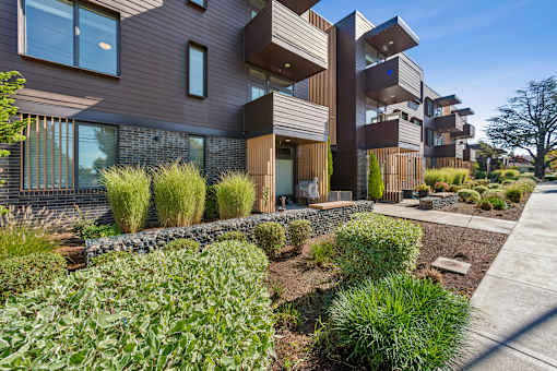 A modern house with a brown exterior and a landscaped front yard.