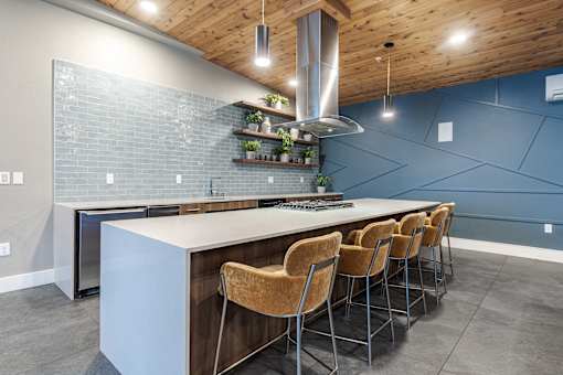 A kitchen with a long white island and brown chairs.