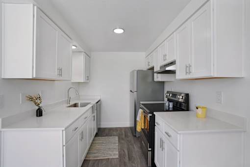 A kitchen with white cabinets and a black refrigerator.