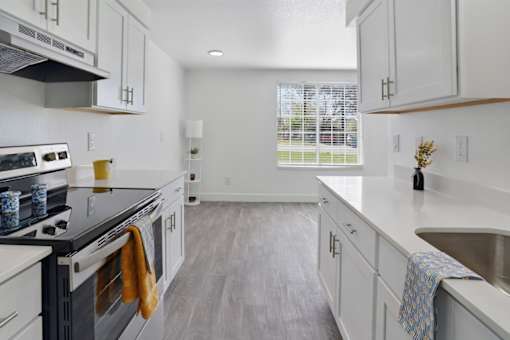 A kitchen with white cabinets and a black stove top.