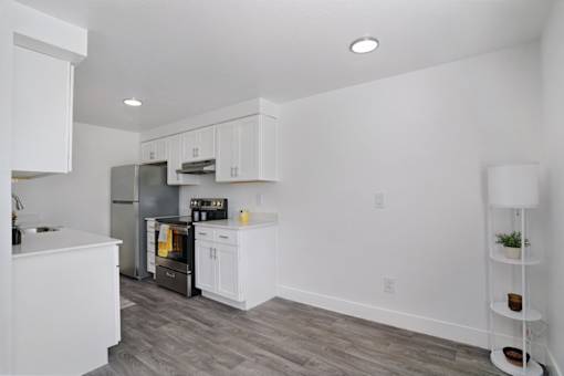 A kitchen with white cabinets and a grey refrigerator.