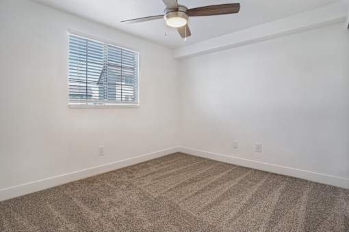 A room with a ceiling fan and carpeted floor.
