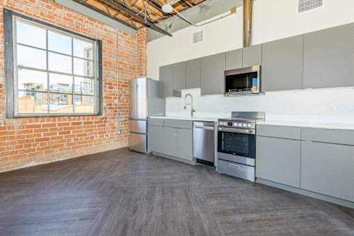 A kitchen with a brick wall and stainless steel appliances.