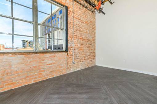 A room with a large window and a brick wall.