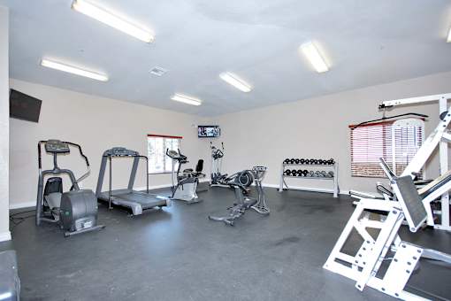 A spacious gym with a variety of equipment including treadmills, stationary bikes, and weight racks.