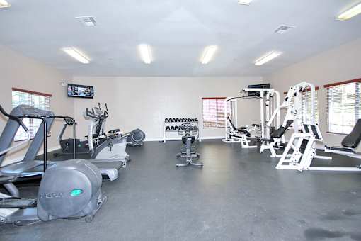 A gym with a variety of equipment including treadmills, weights, and exercise machines.