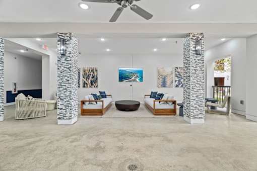 A spacious living room with a ceiling fan and a large painting on the wall.
