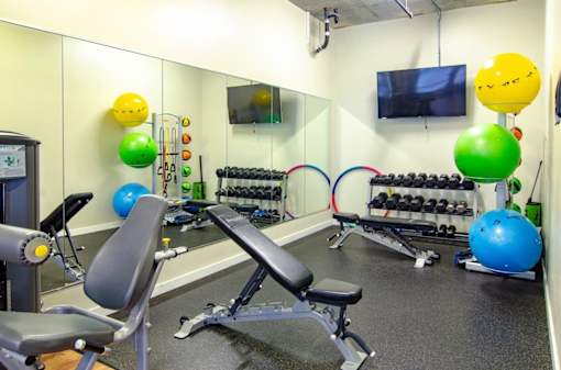 A gym with a variety of equipment including a bench, weights, and exercise balls.