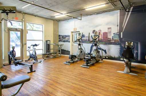 A gym with wooden floors and a city skyline mural on the wall.