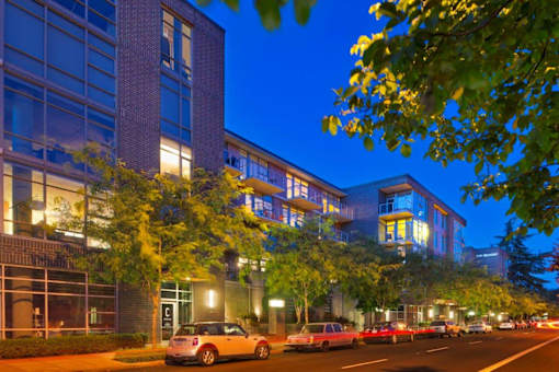 A city street with cars and a building with a lot of windows.