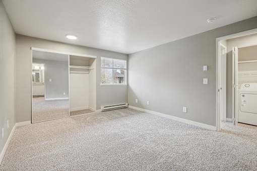 A spacious room with a carpeted floor and a large mirror on the wall.