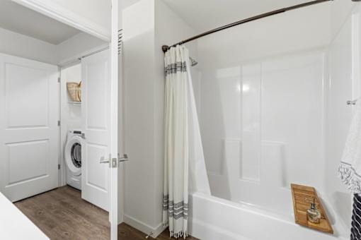 A white bathroom with a tub, towel rack, and a washing machine.