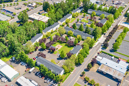 A bird's eye view of a residential area with houses, trees, and parked cars.