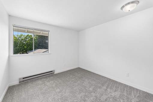A room with a window and a radiator on the floor.