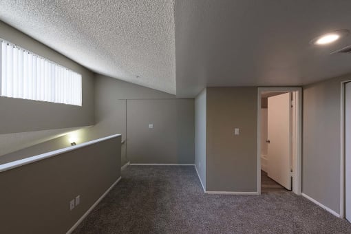 an empty living room with a door to a hallway and a window