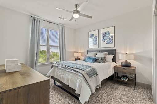A bedroom with a bed, nightstand, and a ceiling fan.