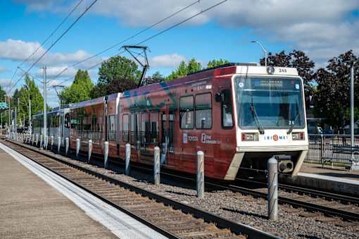 A red and white train is on the tracks with the number 24b on the front.