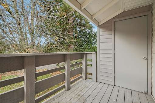 A wooden deck with a white door and a railing.