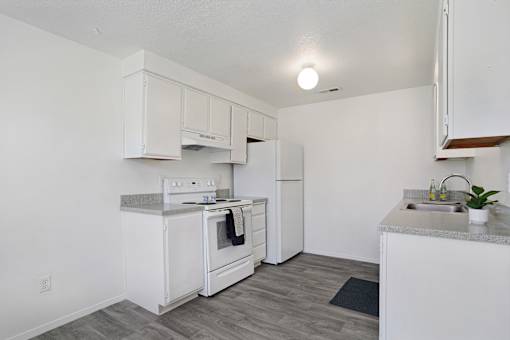 A white kitchen with a stove, oven, and sink.