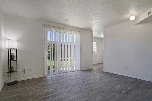A room with a sliding glass door and a wooden floor.