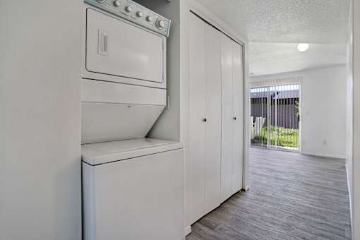 A white fridge in a room with a wooden floor.