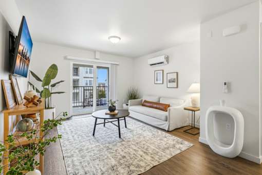 A living room with a white couch, a coffee table, and a large window.
